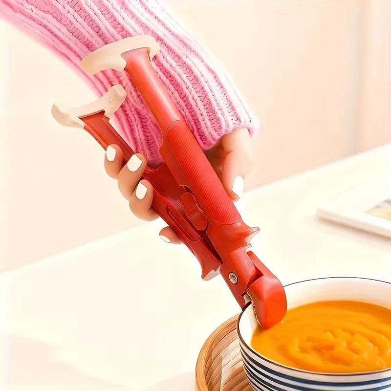 Hand using red automatic soup bowl gripper tool to hold bowl of orange soup on wooden tray