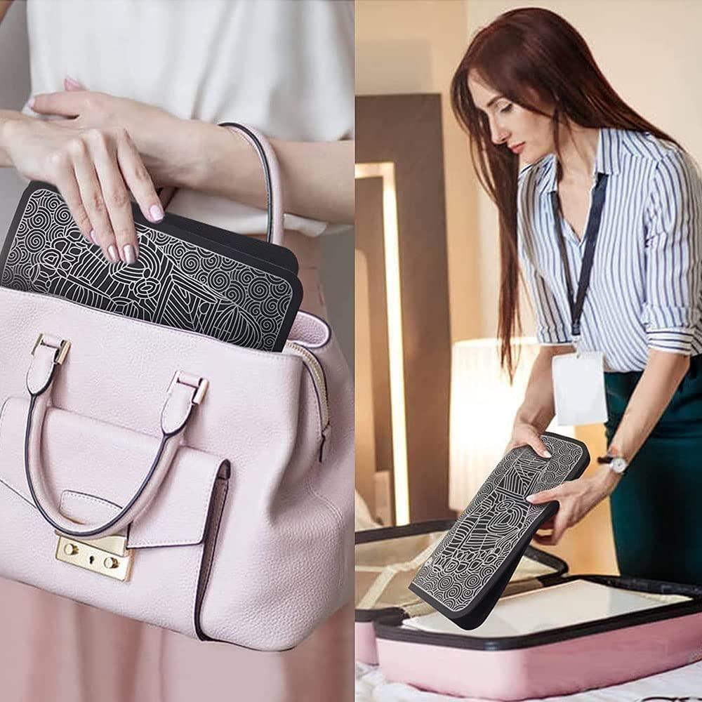 Portable black patterned electronic device for travel placed in pale pink handbag and suitcase.