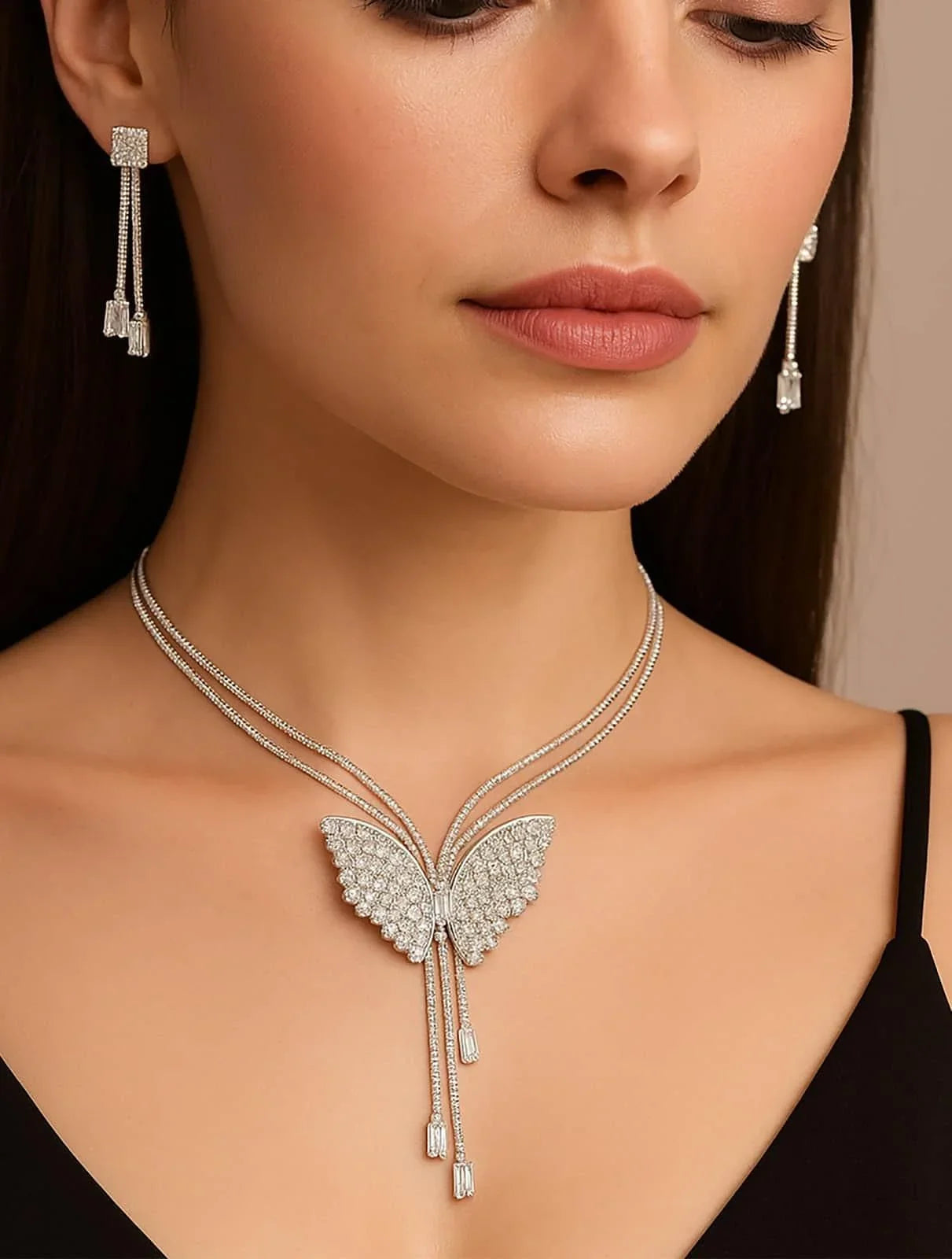 Close-up of woman wearing butterfly-shaped diamond necklace and matching dangling diamond earrings
