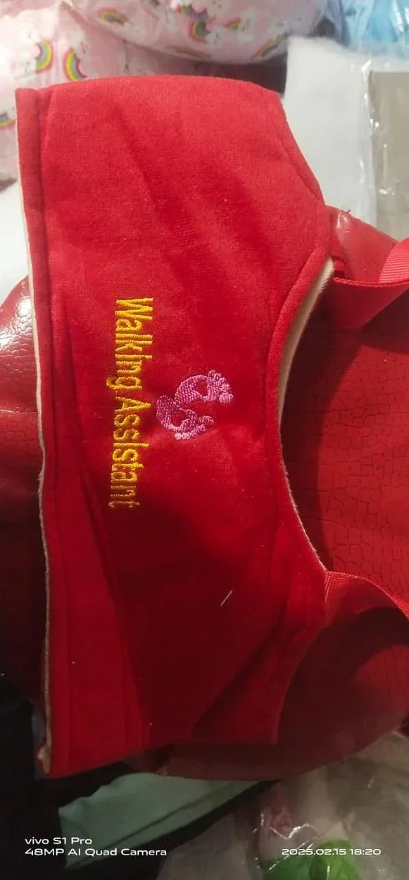 Red fabric walking assistant with yellow and pink embroidery on a textured red surface