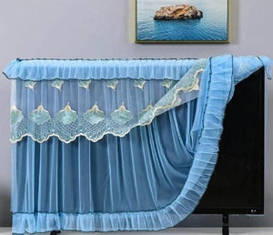 Blue lace TV cover on a television with a framed picture of water in the background